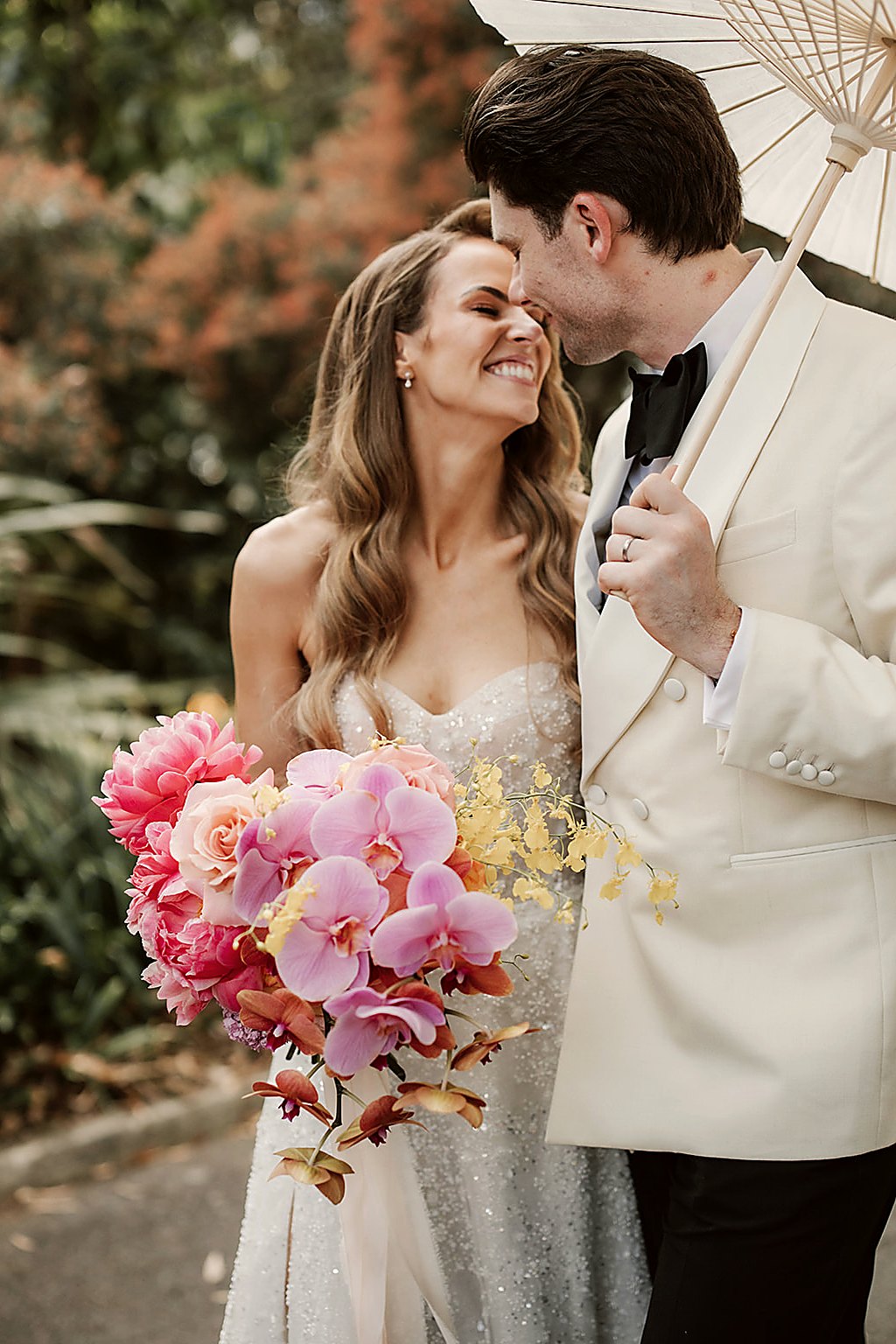 Bride with vivid mixed bouquet under parasol